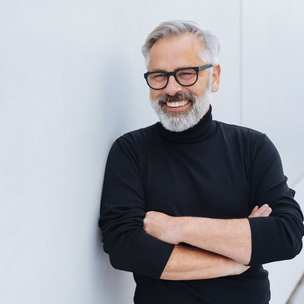 mature man smiling while leaning against a wall